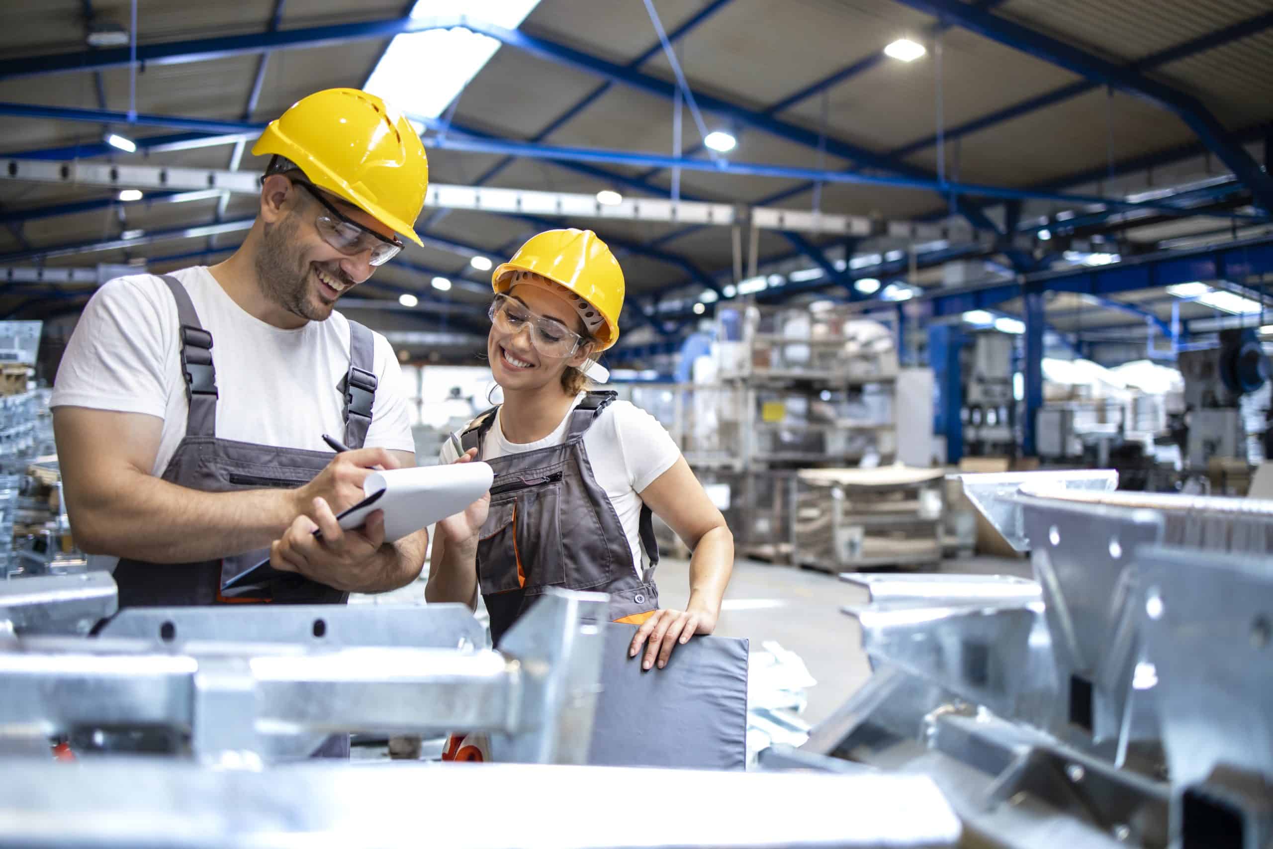 Two workers operating machinery in a factory, focused and wearing protective gear.