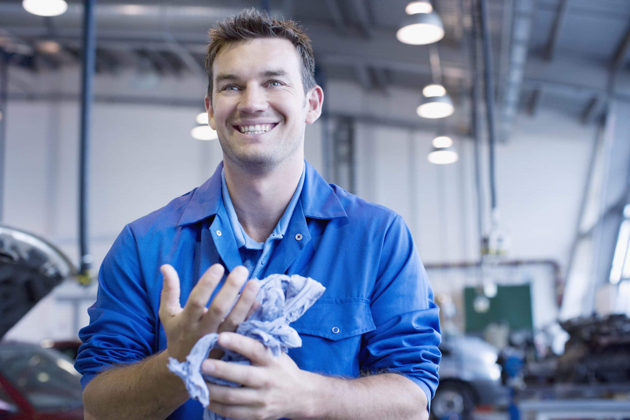 Machinic in blue overalls wiping his hands with a blue wipe